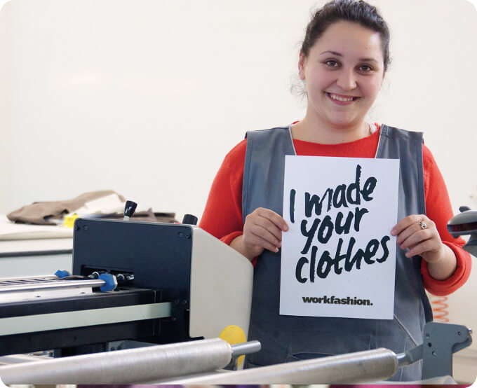 Mitarbeiterin in der Produktion hält ein Schild mit der Aufschrift «I made your clothes»